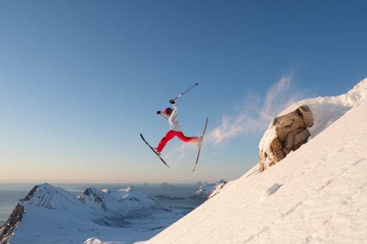 a man flying through the air on a snow covered mountain